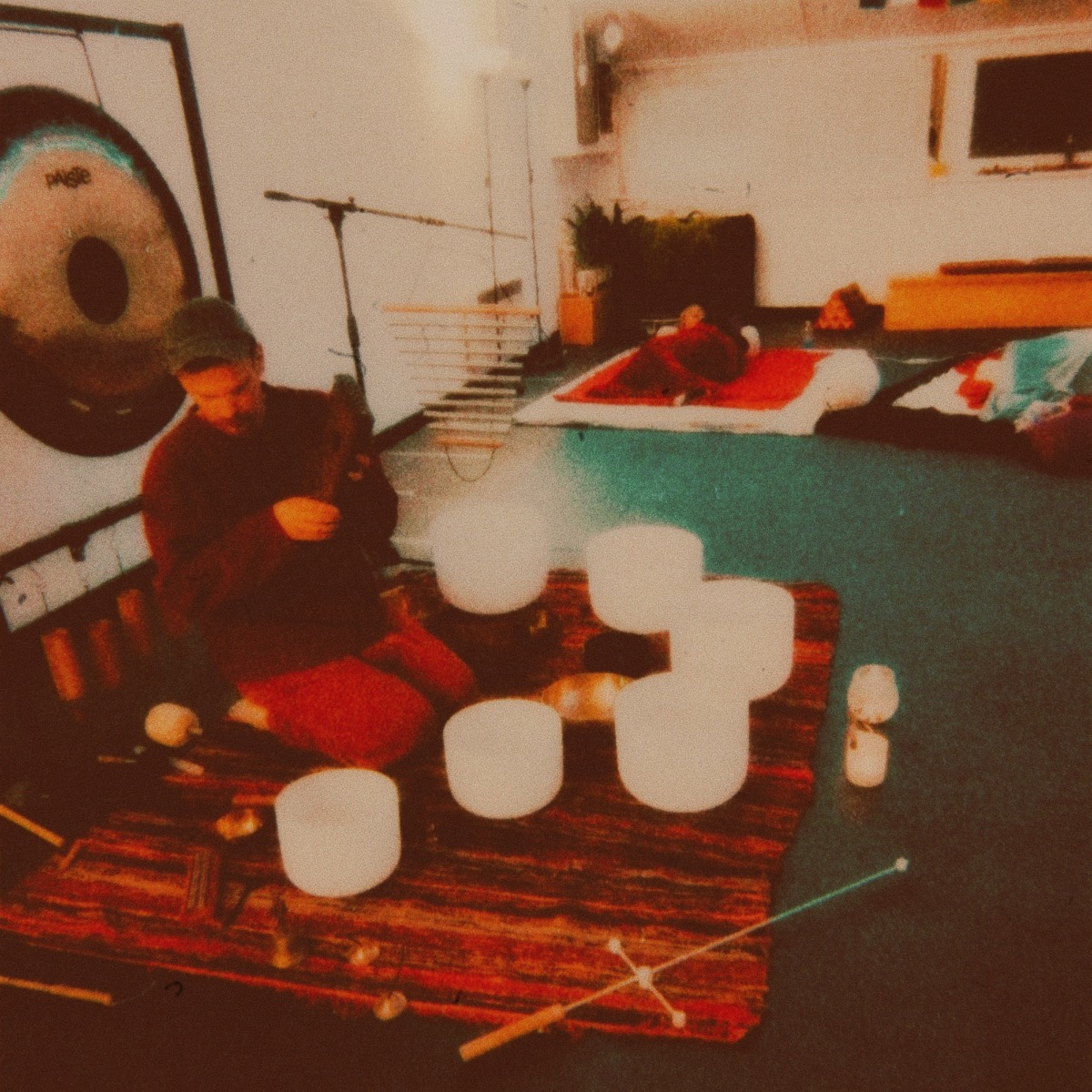 Community setting; crystal bowls on a patterned rug and a gong center stage.