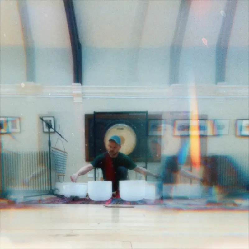 Iain performing with crystal bowls in a bright hall, large gong behind.