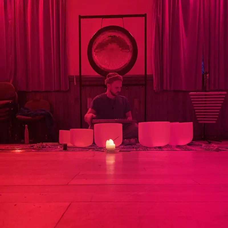 Room with red light, crystal bowls and candle centered, gong behind.