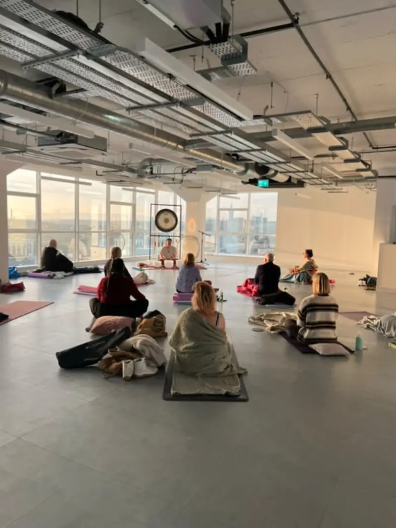 Group soundbath in a high-floor space with city views.